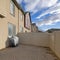 Square Whispy white clouds Backyard of a complex houses with sliding door and fence