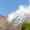 Square Wild forest fire in the mountain emitting thick white smoke against blue sky