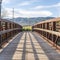 Square Wooden bridge with metal lattice guardrail over a lake with view of mountain