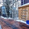 Square Wooden deck with snow shovel and bucket against storage cabinet and gray wall