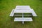 Square wooden picnic table with four benches, on a rain-soaked lawn