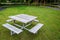 Square wooden picnic table with four benches, on a rain-soaked lawn