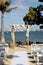 Square wooden wedding arch for outdoor beach yacht club wedding. White chairs and decorated arch for destination waterfront