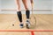 Squash game female player legs, racket and ball