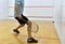 Squash player in action reaching on squash court. White man with racquetball playing match of squash. Sports equipment and
