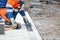 A squatting worker lays down paving slabs with a rubber mallet on a pedestrian stretch of sidewalk