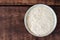 Squeezed white sesame in bowl on wooden background. Benne oilcake. Top view