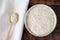 Squeezed white sesame in wooden spoon and in bowl on wooden background and linen. Benne oilcake. Top view