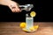 Squeezing lemon into a glass of lemonade with yellow lemons around a white plate