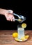 Squeezing lemon into a glass of lemonade with yellow lemons around a white plate