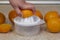 Squeezing orange juice by hand on a manual plastic squeezer.