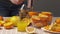 Squeezing an orange with a manual press, close view, making a glass of fresh. Fresh oranges on a wooden table, whole and sliced.