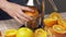 Squeezing an orange with a manual press, close view, making a glass of fresh. Fresh oranges on a wooden table, whole and sliced.