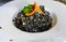 Squid ink risotto with squid rings, served with an orange slice and parsley at a high end restaurant in Montenegro