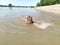 Sremska Mitrovica, Serbia - May 10, 2020. A girl is swimming, looking at the camera and laughing. Sava River. Turbid water in the