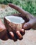 Sri Lankan woman giving an open coconut to drink to a young white man. Close up view with hands and the nut. Fresh coconut water