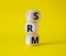 SRM - Sustainability Risk Management symbol. Wooden cubes with word SRM. Beautiful yellow background. Business and Finace and SRM