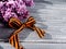 St. George ribbon and lilac branch on a wooden background.