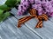 St. George ribbon and lilac branch on a wooden background.
