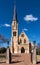 St Marys sandstone church with arched windows and tall steeple in Mudgee Australia against blue sky