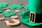 St.Patrick `s Day. celebration. A green leprechaun hat, money and a clover leaf and a horseshoe on a brown background