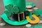 St.Patrick `s Day. celebration. A green leprechaun hat, money and a clover leaf and a horseshoe on a brown background