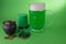 St Patrick`s Day green beer with shamrock, pot with gold coins, horseshoe and Leprechaun hat against green background.