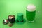 St Patrick`s Day green beer with shamrock, pot with gold coins, horseshoe and Leprechaun hat against green background.