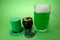 St Patrick`s Day green beer with shamrock, pot with gold coins, horseshoe and Leprechaun hat against green background.