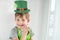 St Patrick`s Day holiday concept. Joyful emotional caucasian blond boy with green paper leprechaun hat with clover on