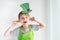 St Patrick`s Day holiday concept. Joyful emotional caucasian blond boy with green paper leprechaun hat with clover pulling the