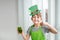 St Patrick`s Day holiday concept. Joyful emotional caucasian boy with green paper leprechaun hat with clover and glass of green