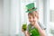 St Patrick`s Day holiday concept. Joyful emotional caucasian boy with green paper leprechaun hat with clover and glass of green