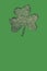 St. Patrick's day vertical background. Clover leaf shape from paper and glitter background with copy space