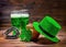 St Patricks day with glasses of green beer, leaf clover, leprechaun hat, horseshoe and pot full gold coins on vintage wooden back