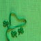 St. Patricks Day or Irish Green Ribbon Heart on Burlap Linen Background with shamrocks and copy space.  It`s square with a trendy