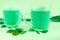 St. Patricks day, two glass beer mugs stand on green background, next to it are clover petals and three gold coins Russian.