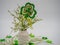 St. Patrickâ€™s Day decor, a white vase filled with white beaded flowers and a large sparkly green four leaf clover surrounded by