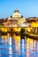 St Peters Basilica in Vatican and Ponte Sant`Angelo Bridge over Tiber River at dusk. Romantic evening cityscape of Rome