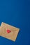 St. Valentine`s envelope, letter of craft paper with red heart on classic blue background with copy space. Vertical