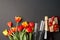 St. Valentine, wedding, Birthday or Mother`s Day. Beautiful red yellow tulips, wine glasses, bottle of wine and gift box on black