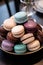 A stack of assorted macarons on a platter, traditional French dessert cookies