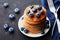 Stack of baked american pancakes or fritters with blueberries and honey syrup on rustic black background. Delicious dessert.