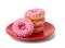 Stack of baked donuts with pink frosting on a red round plate, food isolated on blue background