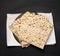 Stack of baked square matzo on a black wooden background