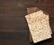 Stack of baked square matzo on a brown wooden background, top view