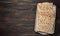 Stack of baked square matzoh on brown wooden background, top view