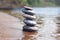 Stack of balancing pebble stones on sand and water edge as zen symbol