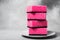 A stack of barbie pink dishwashing sponges on a white plate close-up on a neutral gray background. Gentle dishwashing. House