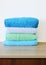 Stack of bath towels on light wooden background closeup.Pile of rainbow colored towels.Top view.